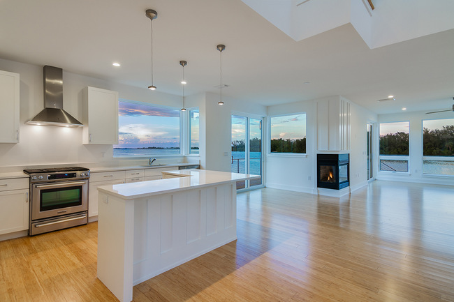 Contemporary open-concept kitchen with white cabinets and large corner Hurricane Windows in Pinellas County, FL looking out to the water.