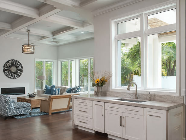 Modern coastal home with white-framed hurricane windows in Pinellas County, FL, offering palm tree views and safety.