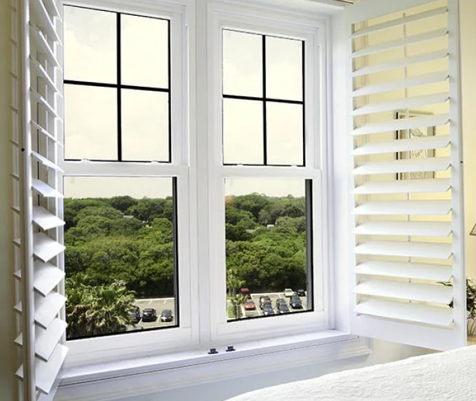 Bright interior featuring hurricane windows St. Petersburg, FL with white shutters and green outdoor view