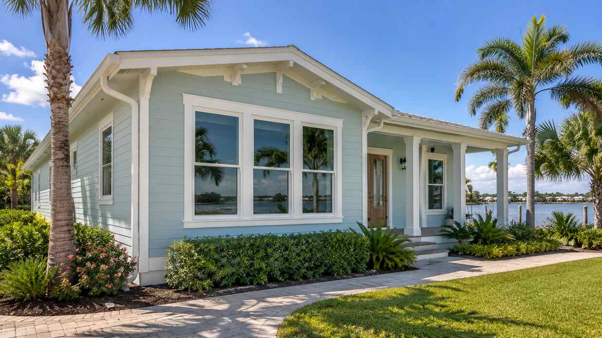 Coastal home exterior with white replacement windows and tropical landscaping